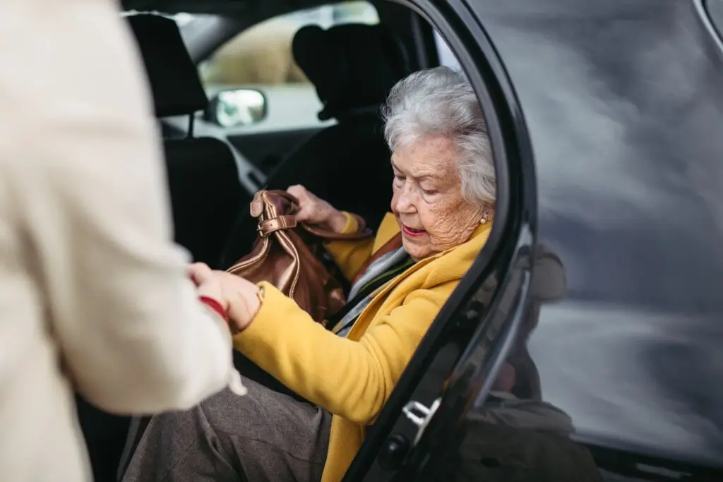 caregiver helping an elderly woman out of car